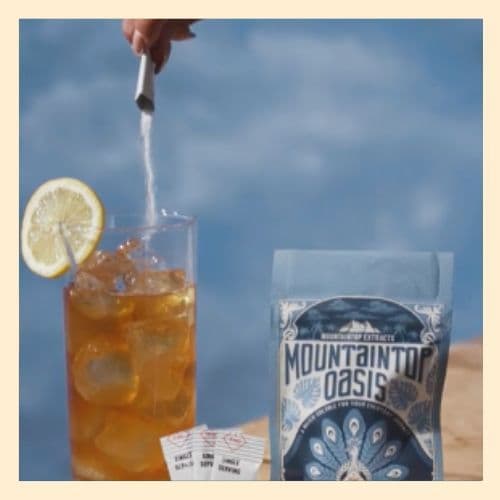 photo of a glass of iced tea with lemon, and dissolvable cannabis being poured into the glass, next to a package of Mountaintop Extracts Oasis dissolvable cannabis.