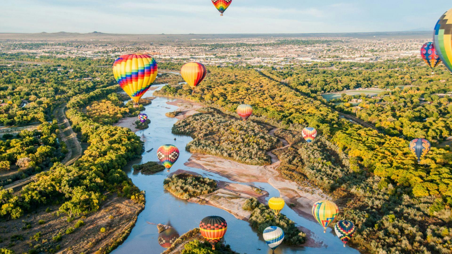 a stock image of a dozen multi-colored hot air balloons in flight over New Mexico.
